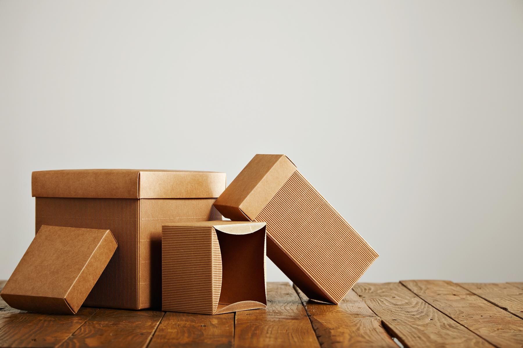 Set of three unlabeled similar craft cardboard boxes with covers beautifully arranged in a studio with white walls